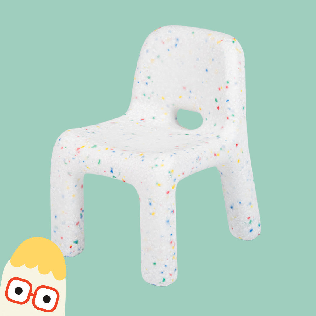 White chair-shaped cushion with colorful speckles on a green background