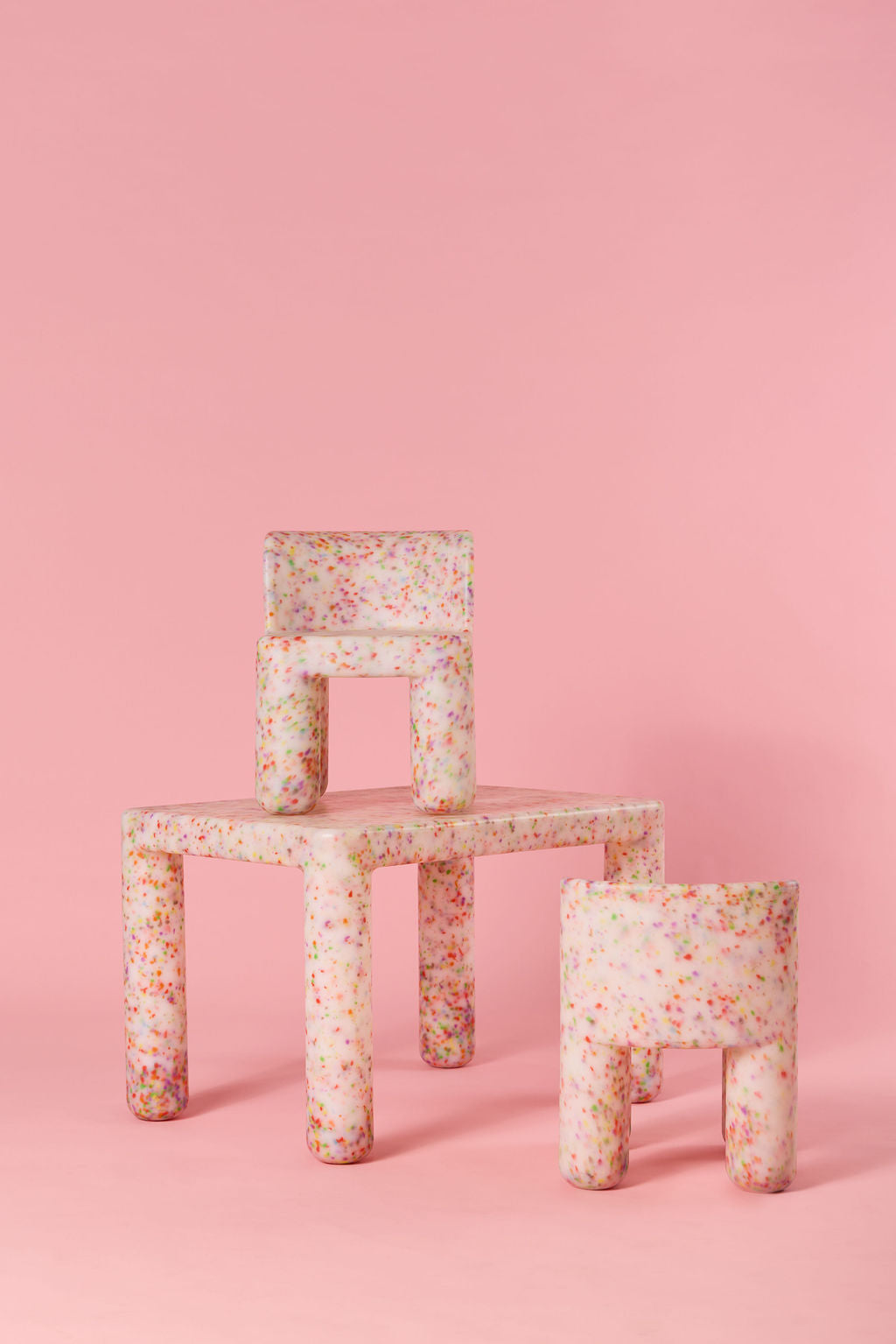 Floral-patterned chair and stool set against a pink background