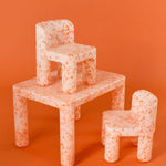 Children's furniture set with table, chairs, and bench on an orange background