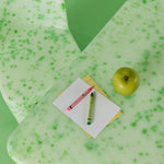 Green textured desk mat with a notebook, pen, and apple on a green background