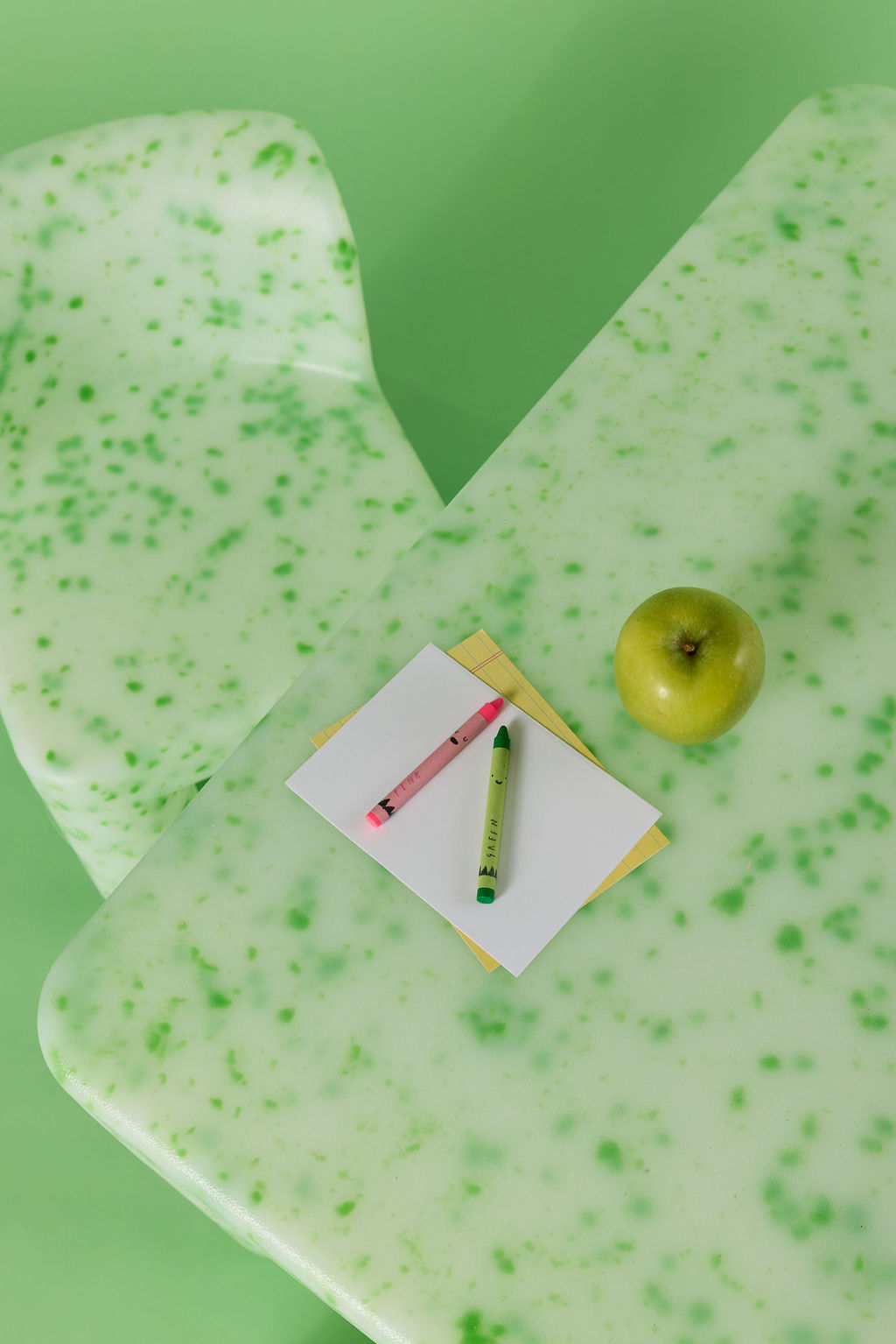 Green textured desk mat with a notebook, pen, and apple on a green background