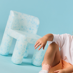 Person sitting on a unique chair with a blue background