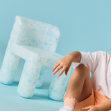 Person sitting on a unique chair with a blue background