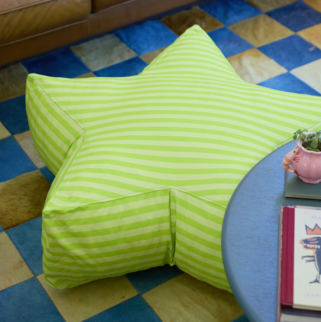 Green striped bean bag chair on a checkered floor with a small table and plant in the foreground.