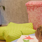 Green stripped bean bag next to Red Rollie bin