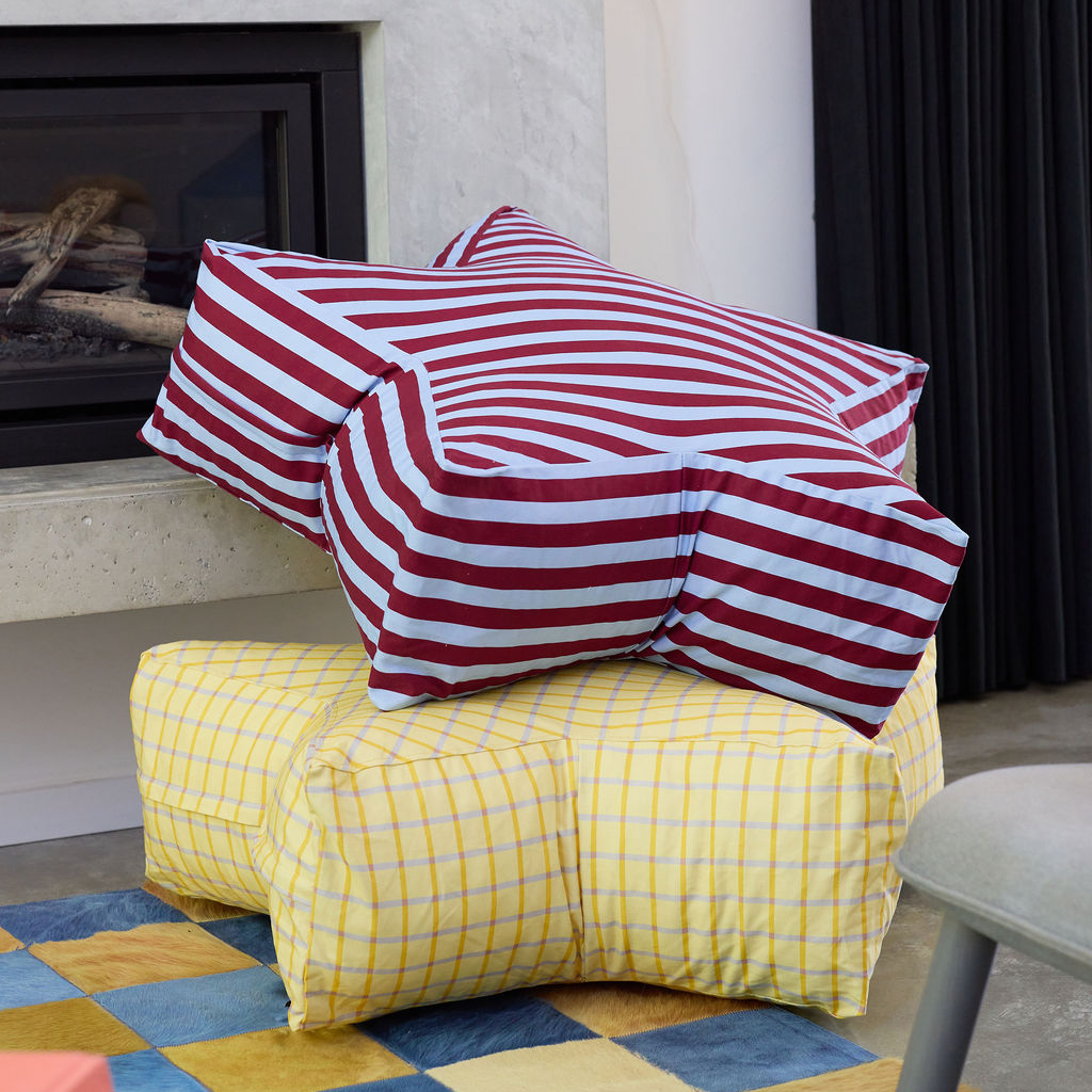 Yellow checkered ottoman with red and white striped pillows in a living room setting.