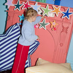 Child playing with decorative stars on a pink fireplace in a child's bedroom.