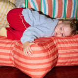 Child lying on a red striped bed with a green metal frame