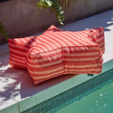 Red and pink striped star shaped bean bag by a poolside
