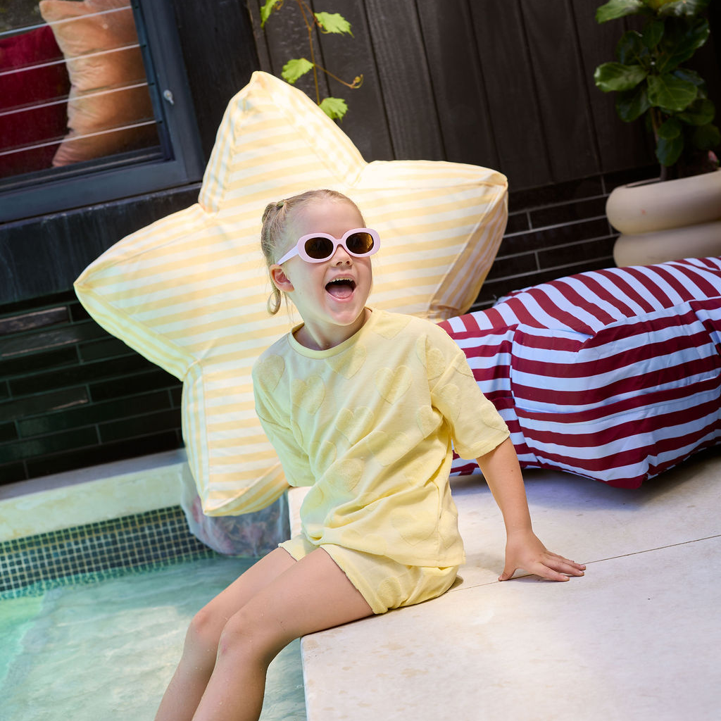 GIRL SITTING BY THE POOL NEXT TO YELLOW STAR OUTDOOR BEAN BAG AND BLUE AND DARK RED OUTDOOR BEAN BAG