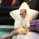Child sitting on a star-shaped inflatable chair by a poolside.