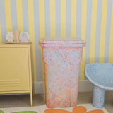Children's room with colorful striped wallpaper, a trash can, and a rug with flower designs.