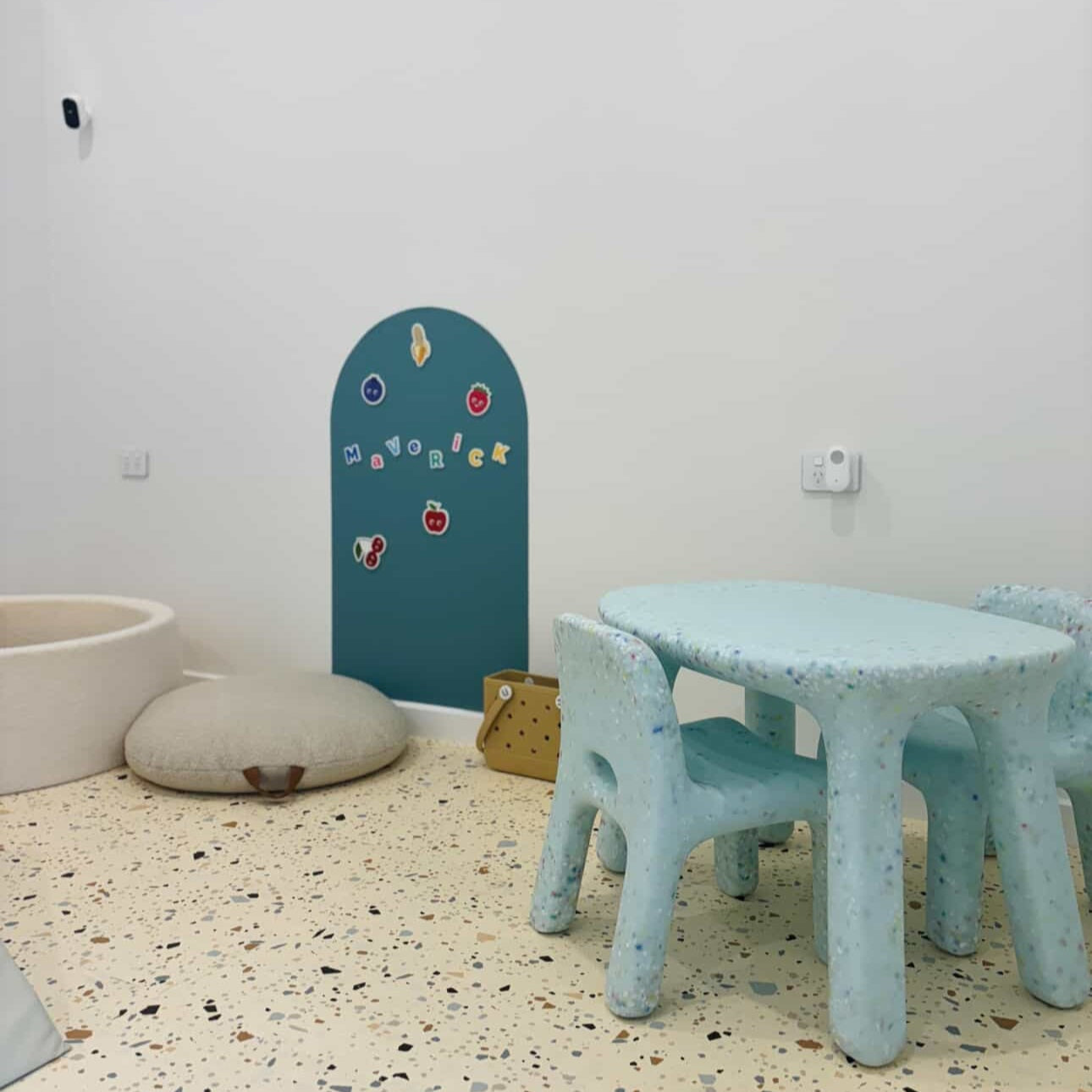 Children's playroom with light blue table and chairs against a white wall.