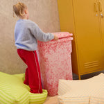 Child playing with colorful furniture in a room with a yellow cabinet.