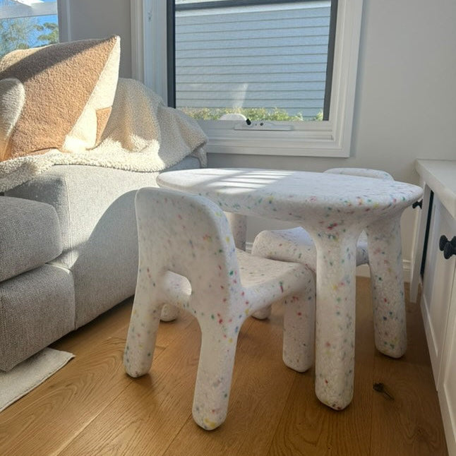 Children's table and chairs in a living room setting with a couch and window in the background.