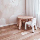 Children's furniture including a small table and chair in a room with light-colored walls and flooring.
