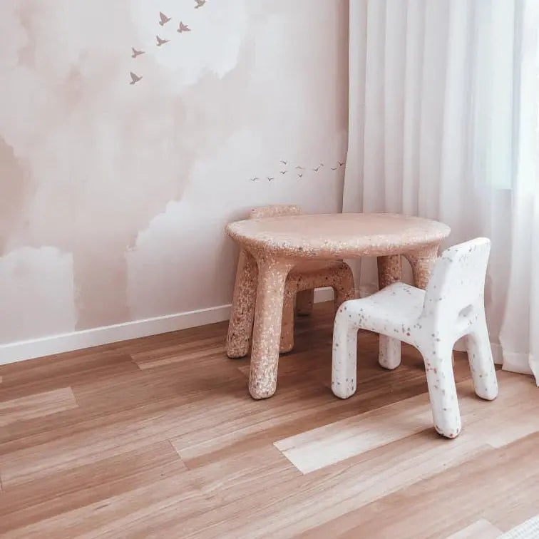 Children's furniture including a small table and chair in a room with light-colored walls and flooring.