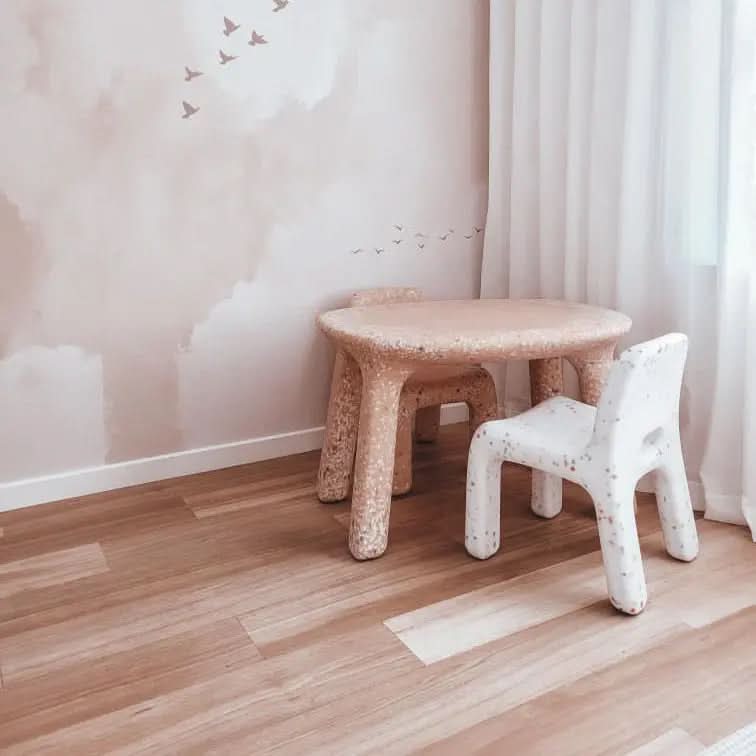 Children's furniture including a small table and chair in a room with light-colored walls and flooring.
