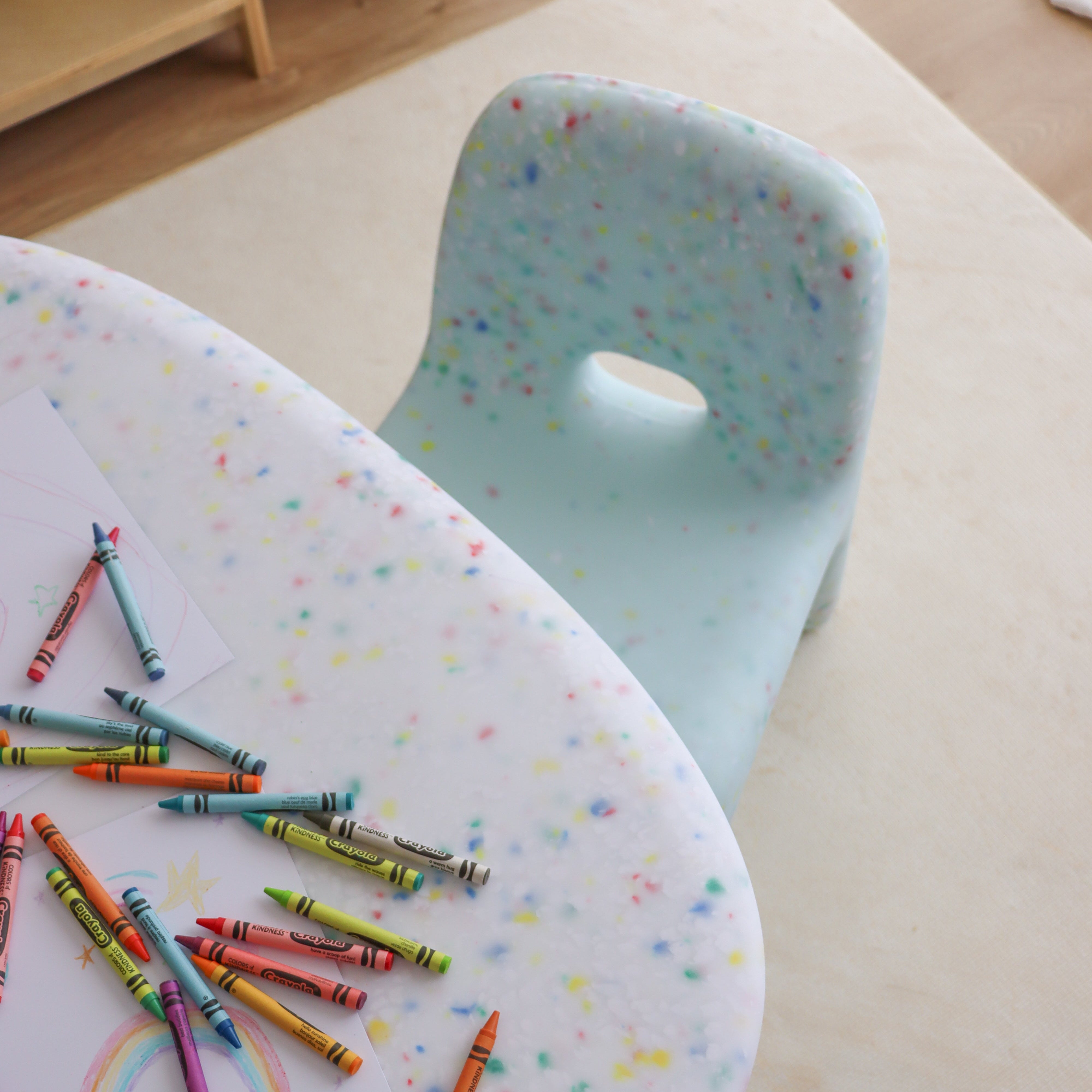 Colorful crayons on a polka dot table with a chair in the background