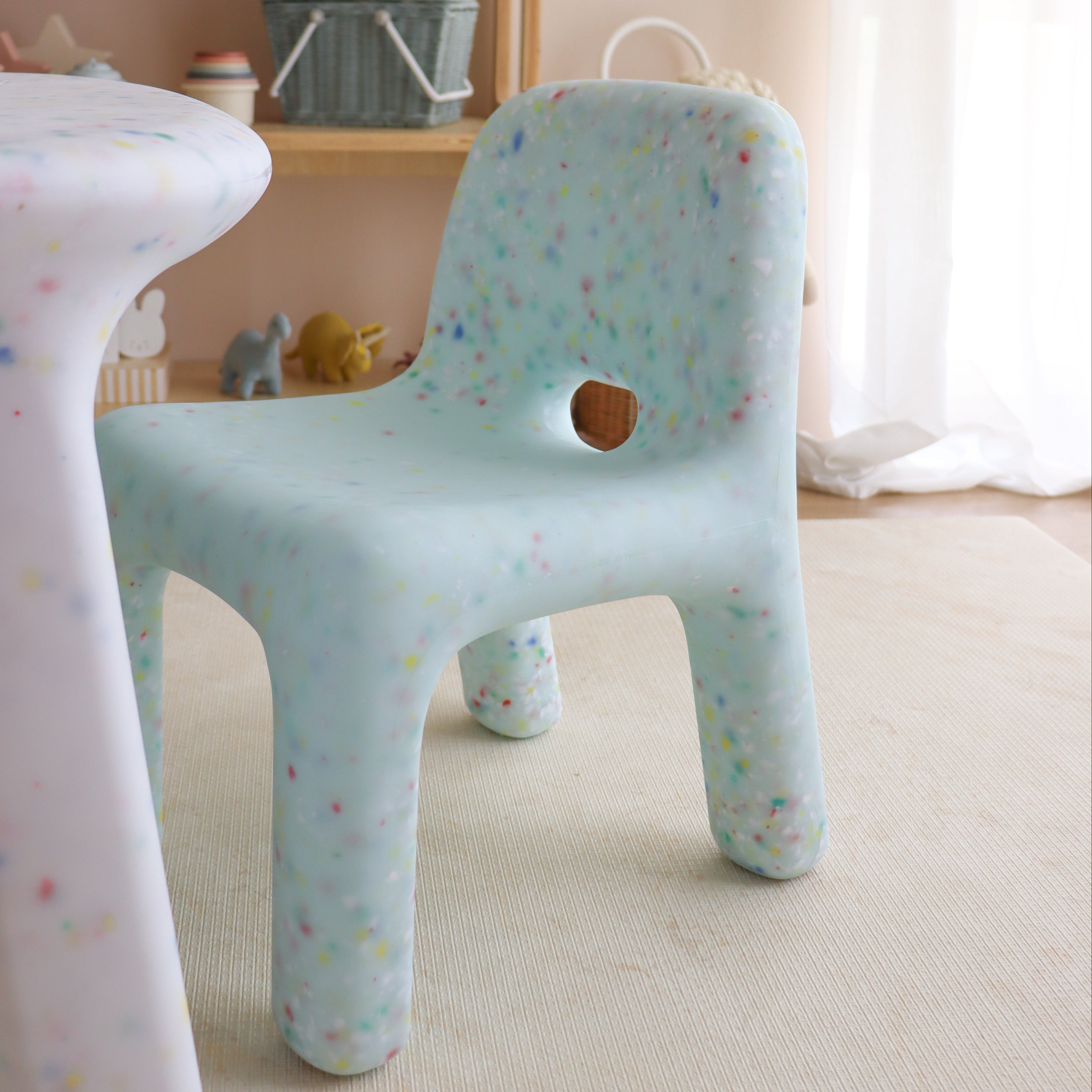 Children's chair with colorful pattern in a room with toys and furniture.