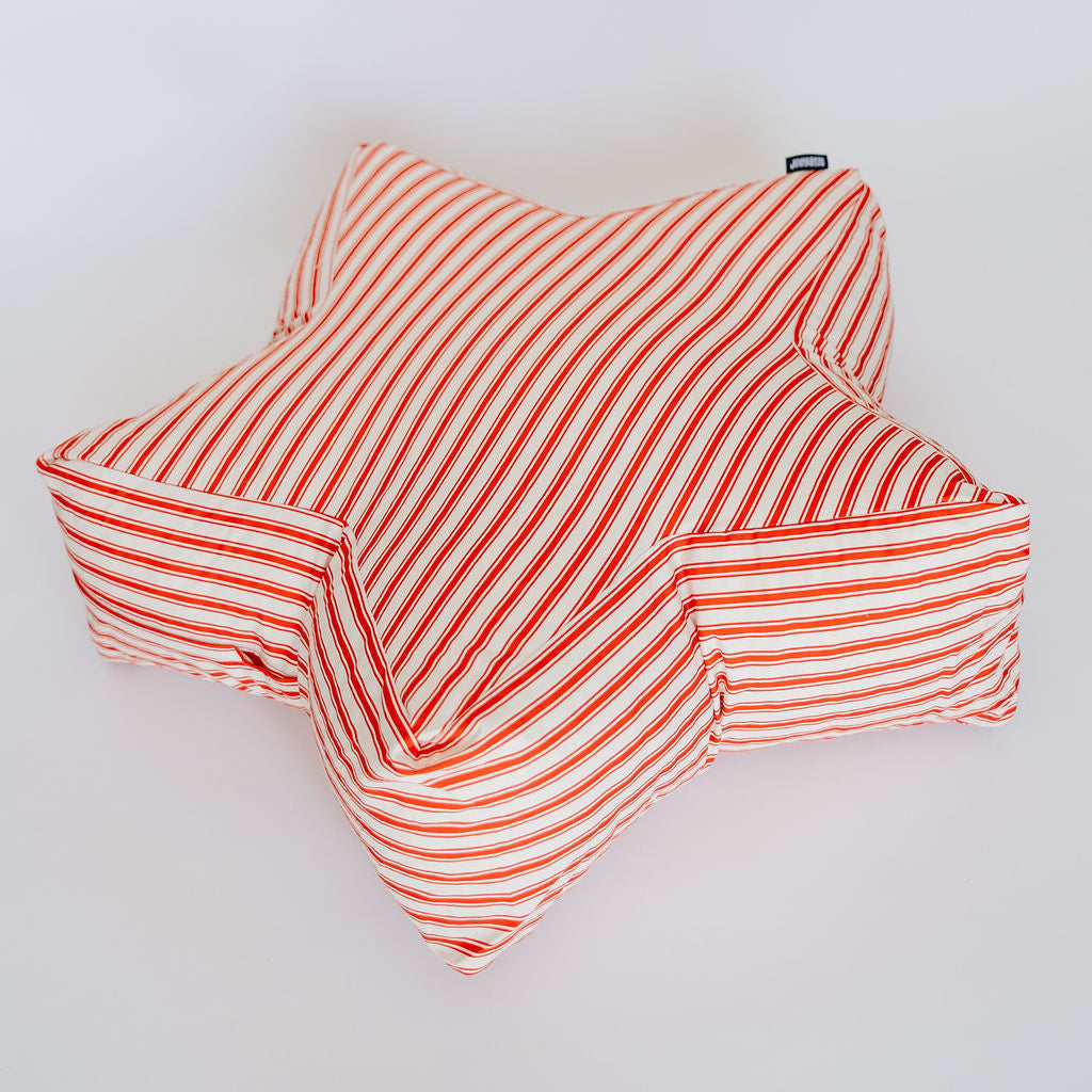 A star-shaped plush cushion with a red and white striped pattern, photographed on a clean white background.