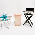 Decorative items including a star-shaped object, a black director's chair with a decorative item, and a pink woven basket on a white background.