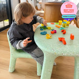Child playing with colorful toys at a green table indoors