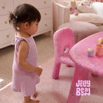Child in a pink-themed room with a 'Jelly Bean' table