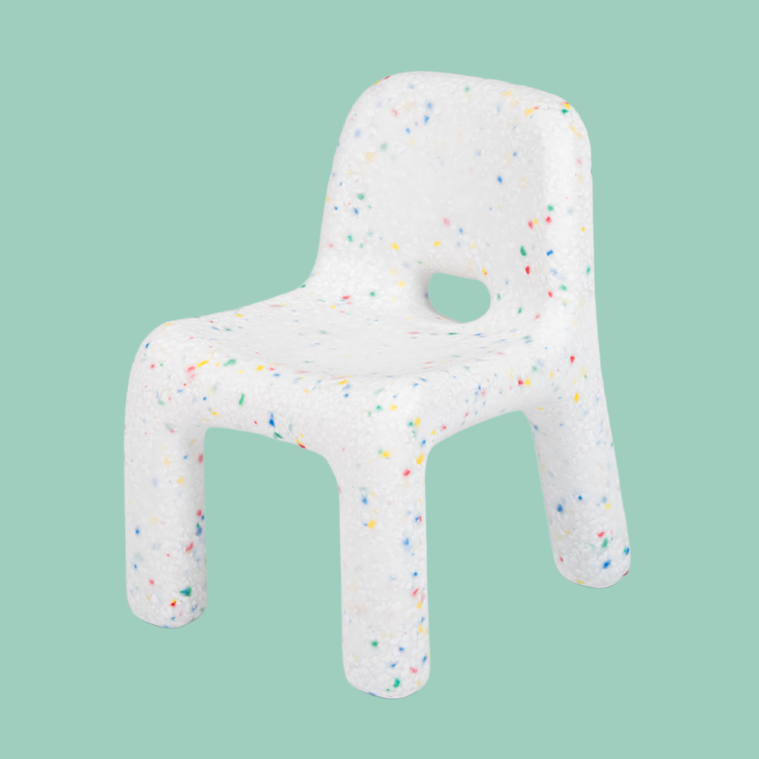 White chair-shaped cushion with colorful speckles on a light green background